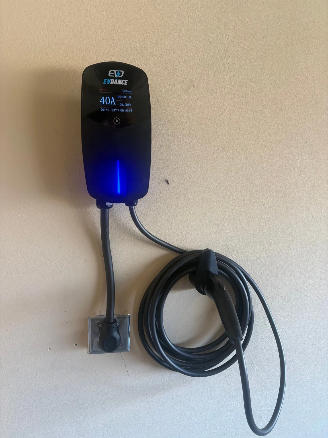 Wall-mounted EV charger with its charging cable and receptacle