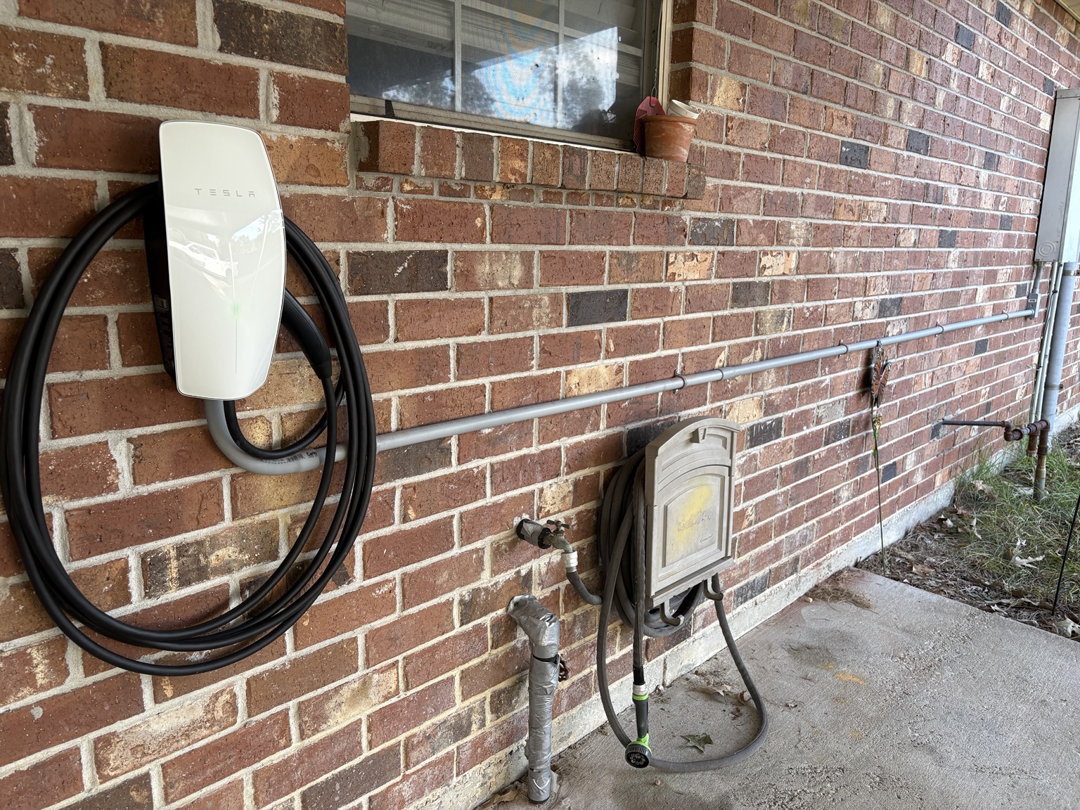 Tesla Wall Connector and exterior conduit installed along the brick wall at this Walker project
