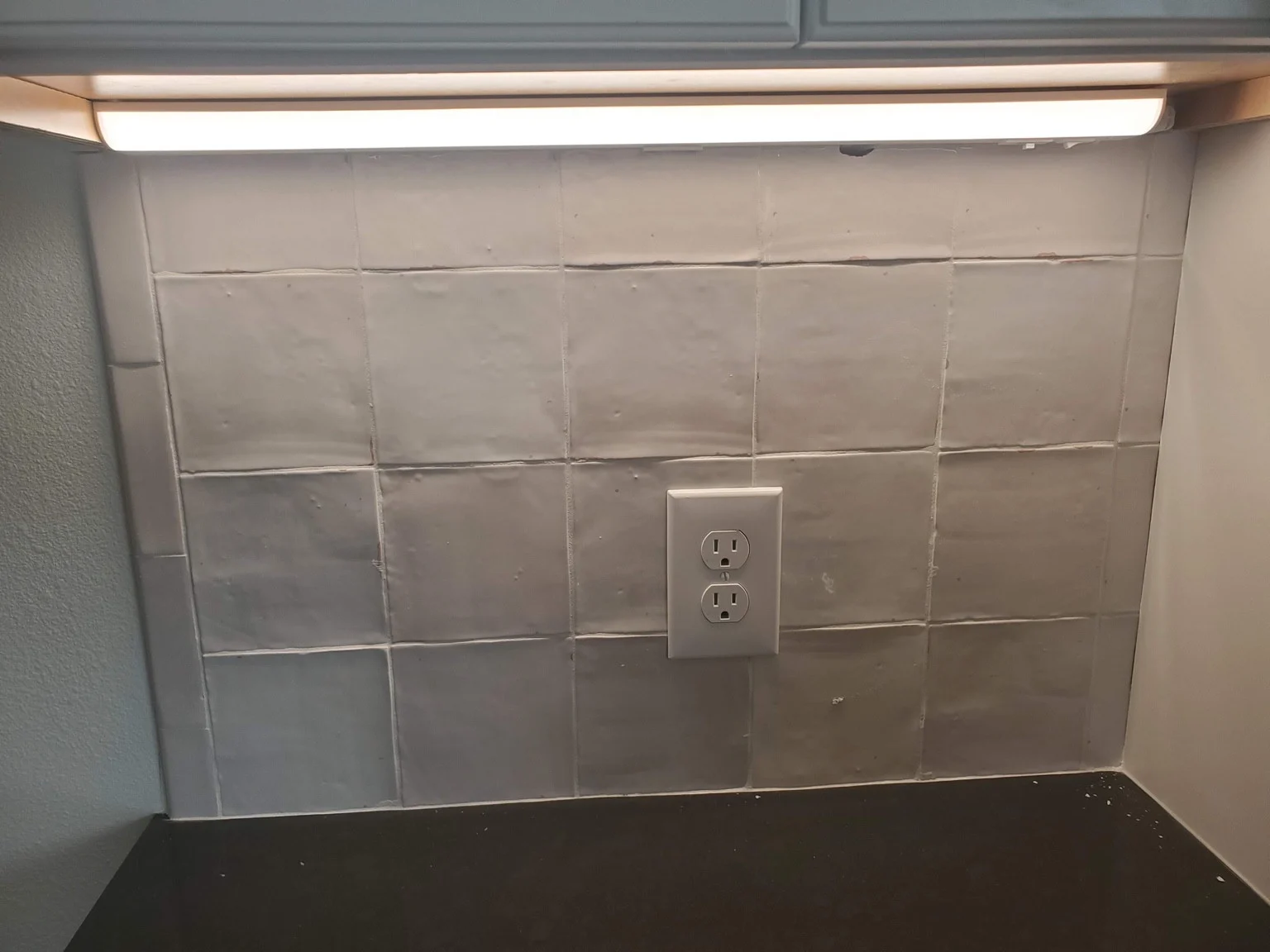 Under-cabinet light illuminating a kitchen counter and backsplash
